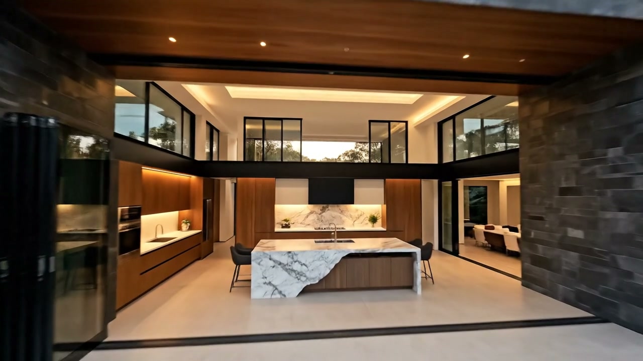 Double-height kitchen and living interior with marble waterfall island, timber cabinetry and black-framed glazing